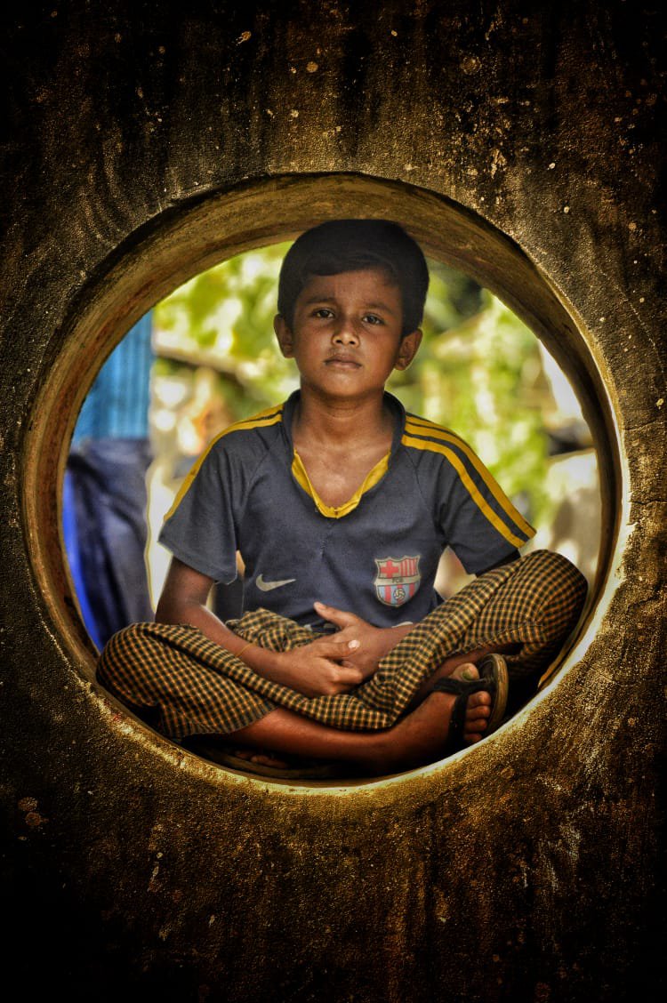 A Rohingya boy is sitting inside the hole