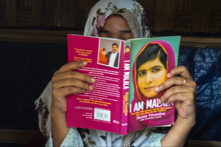 A Rohingya girl is reading the book I am Malala